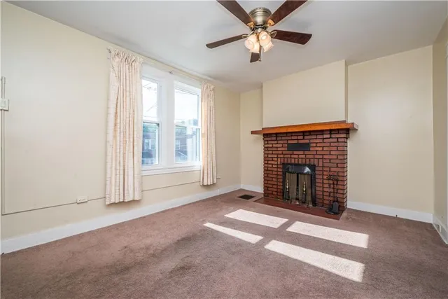 an empty room with windows fireplace and fan