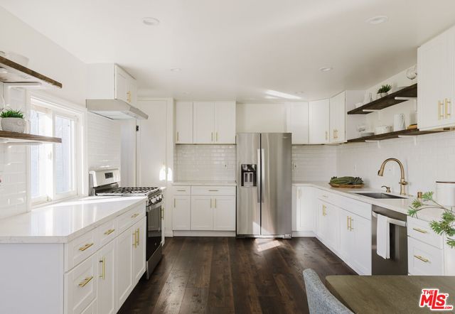 a kitchen with stainless steel appliances granite countertop a sink a stove and wooden cabinets