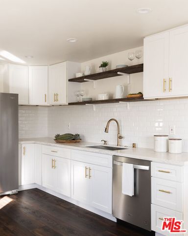 a kitchen with stainless steel appliances a white table chairs and a wooden floor