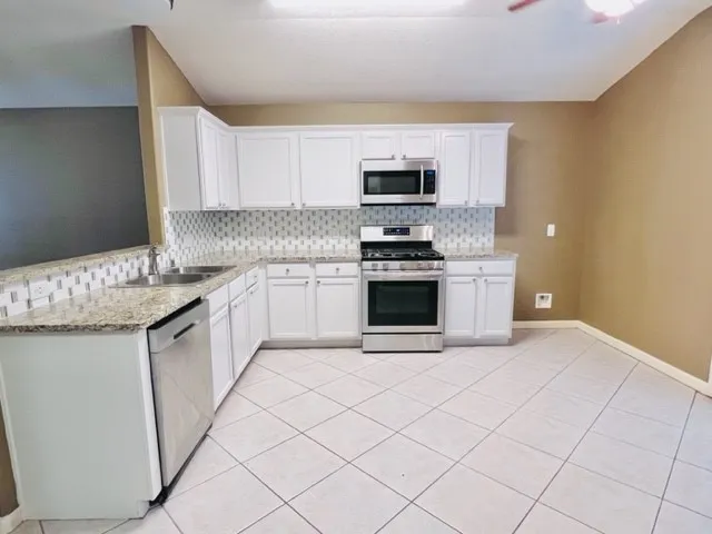a kitchen with stainless steel appliances granite countertop a sink stove and microwave