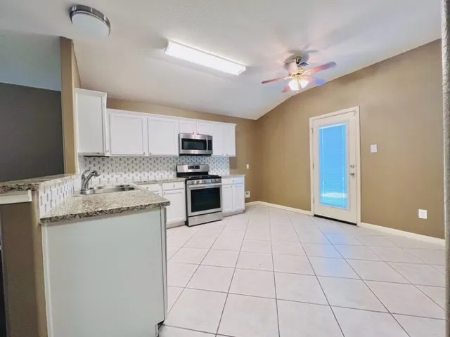 a kitchen with granite countertop a sink cabinets and stainless steel appliances