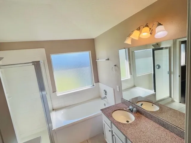 a bathroom with a granite countertop sink vanity mirror bathtub and shower