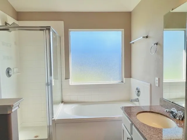 a bathroom with a granite countertop sink a mirror and a bathtub