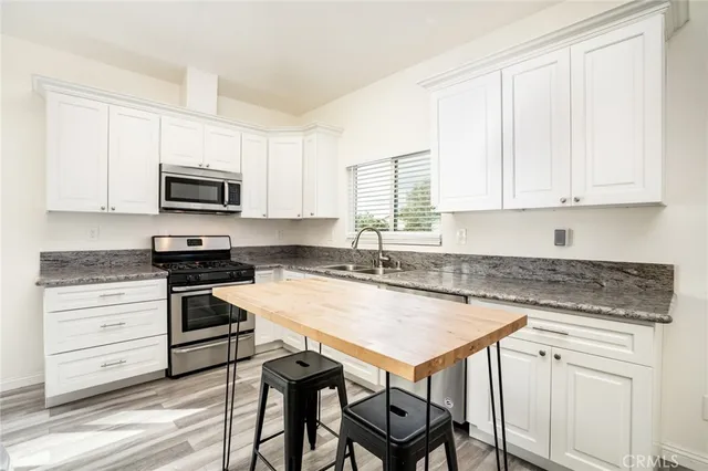 a kitchen with granite countertop white cabinets and stainless steel appliances