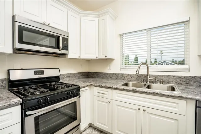 a kitchen with granite countertop white cabinets and appliances