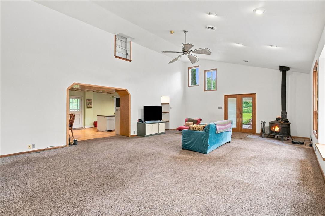 3408 Oak Hill Road Emmaus, PA 18049 - Photo 14 of 93 A spacious living room displays carpeted flooring and a wood stove beneath tall vaulted ceilings.