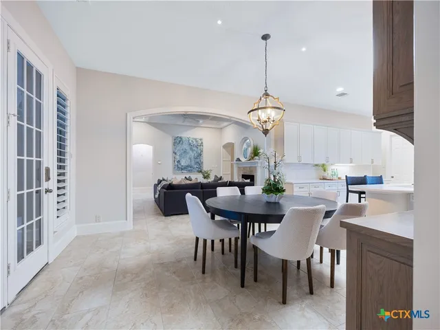 a view of a dining room and livingroom with furniture wooden floor a rug a painting and a chandelier
