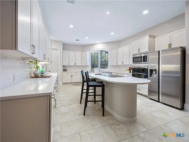 a kitchen with stainless steel appliances granite countertop a stove a sink a microwave a refrigerator and cabinets