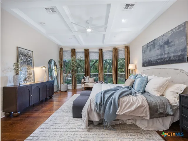 a bedroom with a bed wooden floor and large windows