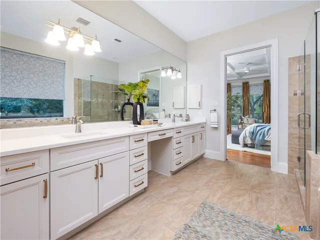 a spacious en suite bathroom with double sink and a large mirror