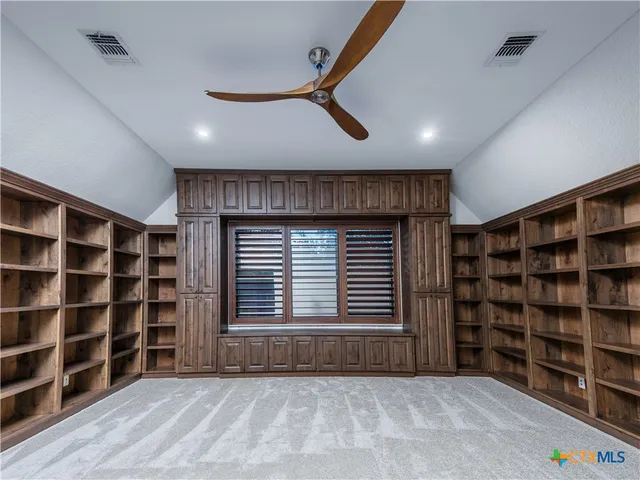 a view of an empty room with shelves and a window