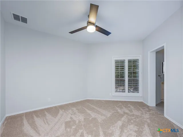 an empty room with windows and ceiling fan