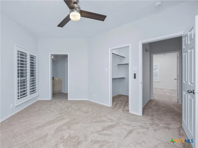 a view of an empty room with a ceiling fan and window