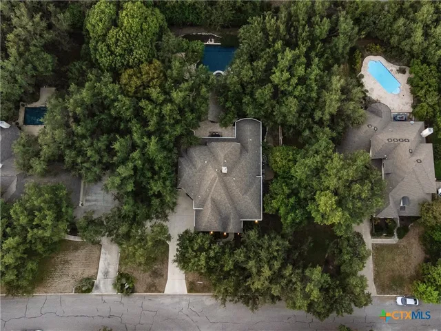 an aerial view of a house with a yard and trees all around