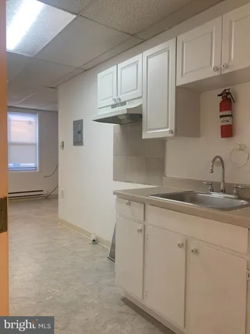 a kitchen with white cabinets and sink