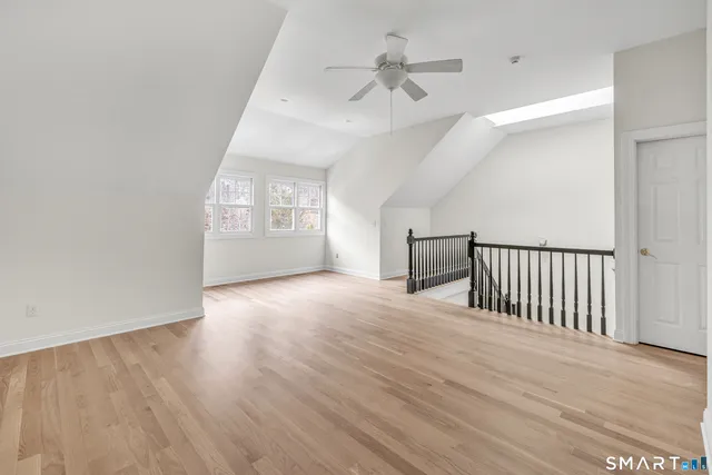an empty room with wooden floor chandelier and windows