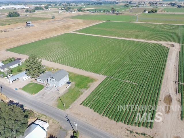 1520 Scheloske Road Weiser, ID 83672 - Photo 41 of 42 Expansive agricultural property featuring cultivated fields, a detached garage, and a two-story residence with a gray exterior