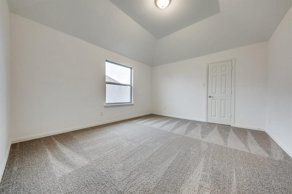 104 Sweetleaf Drive Red Oak, TX 75154 - Photo 25 of 36 This room features plush carpet flooring, a window providing natural light, a white paneled door, and a vaulted ceiling with a flush-mount light fixture