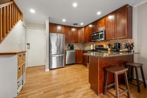 a kitchen with kitchen island granite countertop wooden cabinets and stainless steel appliances