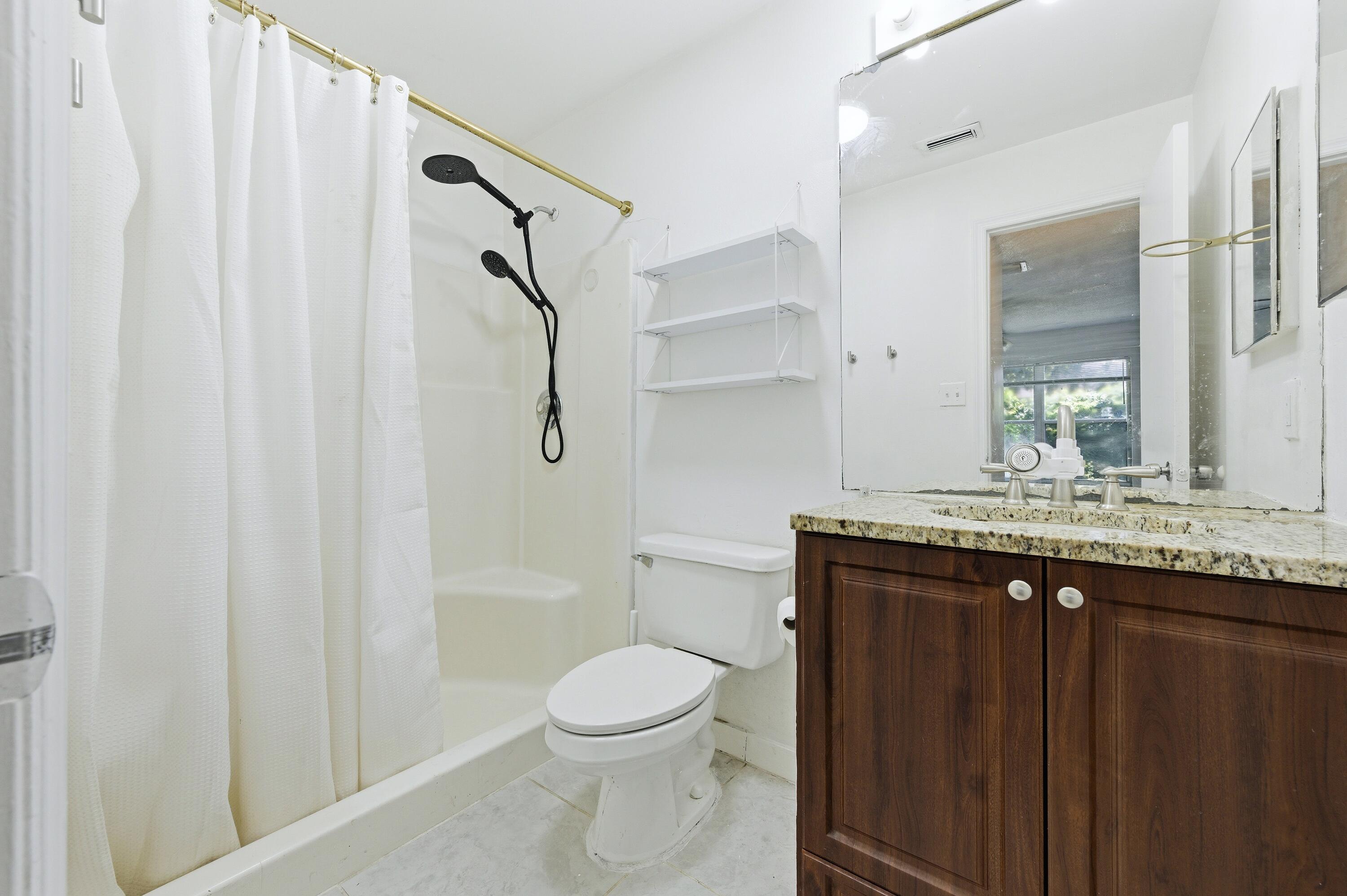 6088 Heather Street Jupiter, FL 33458 - Photo 12 of 18 a bathroom with a granite countertop sink toilet and shower