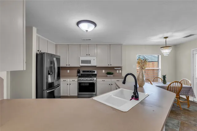 a kitchen with stainless steel appliances granite countertop a sink a stove a refrigerator and a refrigerator