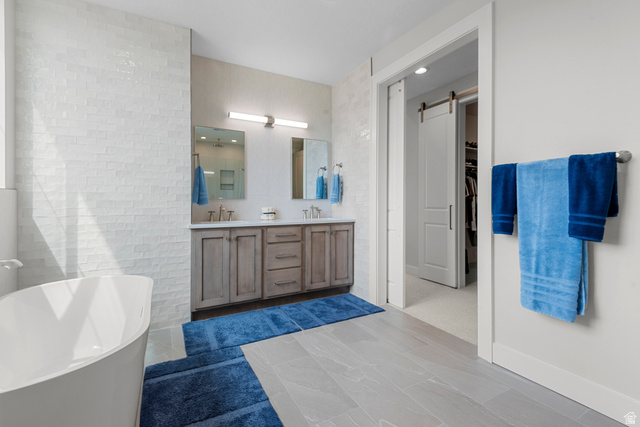 250 South Main Street, Unit 24 Alpine, UT 84004 - Photo 21 of 50 Bathroom with a freestanding bath, double vanity, tile walls, dark tile patterned floors, and a walk in closet