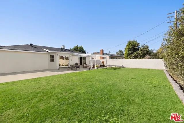 a view of a white house with a big yard and large trees