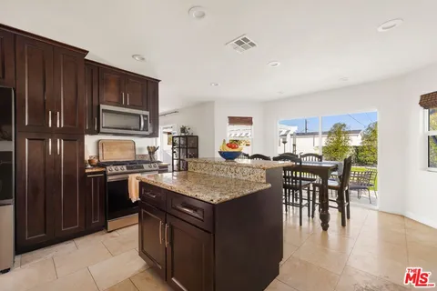 a kitchen with stainless steel appliances granite countertop a stove top oven a sink dishwasher a dining table and chairs