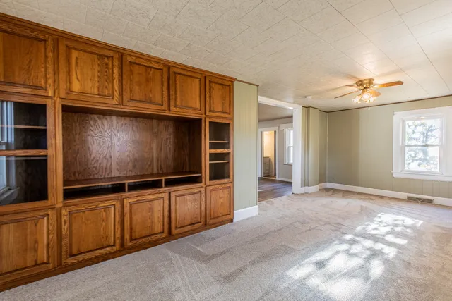 a view of an empty room with cabinet and window