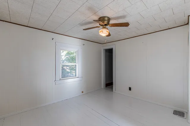 an empty room with windows and fan