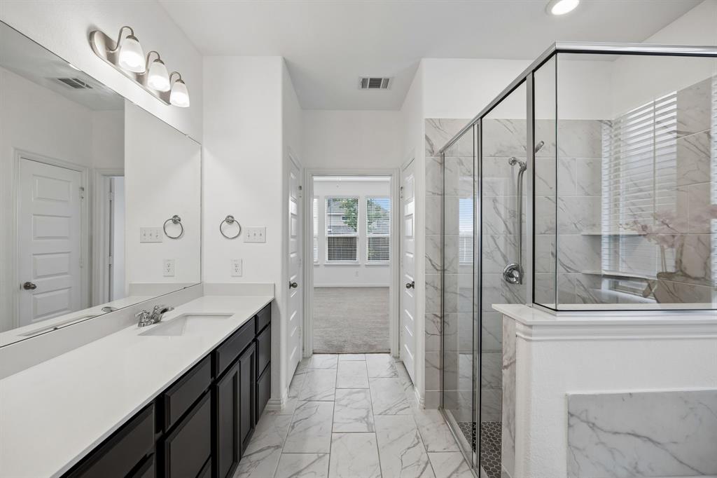 1303 Wheelwright Drive Forney, TX 75126 - Photo 33 of 39 Spacious bathroom featuring a glass-enclosed shower with tile surround, a double vanity with ample counter space, and modern light fixtures