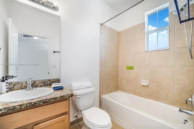 a bathroom with a granite countertop sink toilet mirror and bathtub