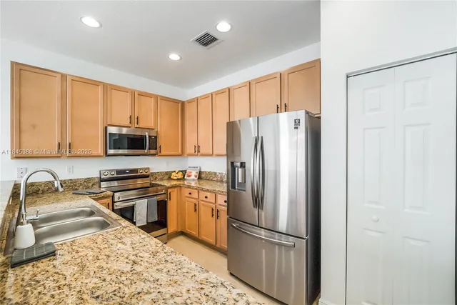 a kitchen with stainless steel appliances granite countertop a refrigerator a stove top oven a sink and dishwasher