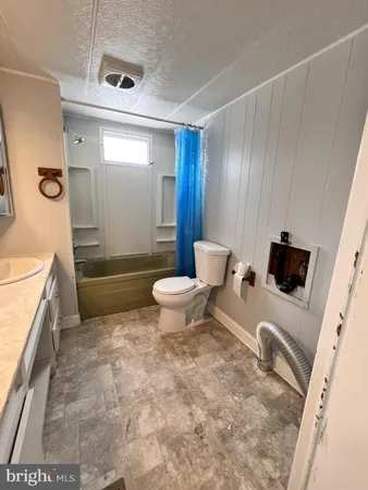 a spacious bathroom with a granite countertop sink mirror toilet bathtub and vanity