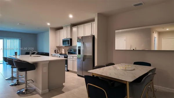 a kitchen with a refrigerator a stove a sink dishwasher with a dining table and chairs