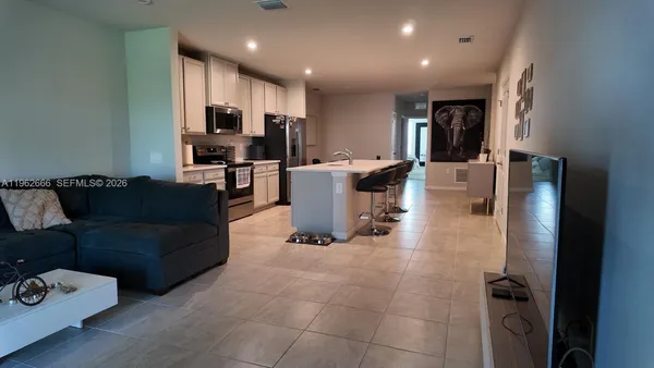 a living room with couches and kitchen view with wooden floor