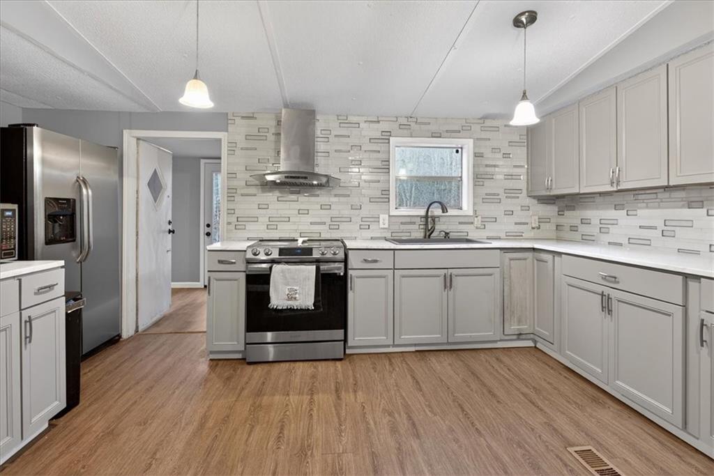 323 Ball Field Road Waleska, GA 30183 - Photo 8 of 39 a kitchen with stainless steel appliances granite countertop wooden floors and white cabinets
