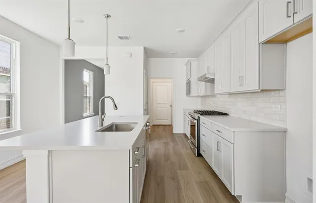 a kitchen with stainless steel appliances granite countertop a sink stove and refrigerator