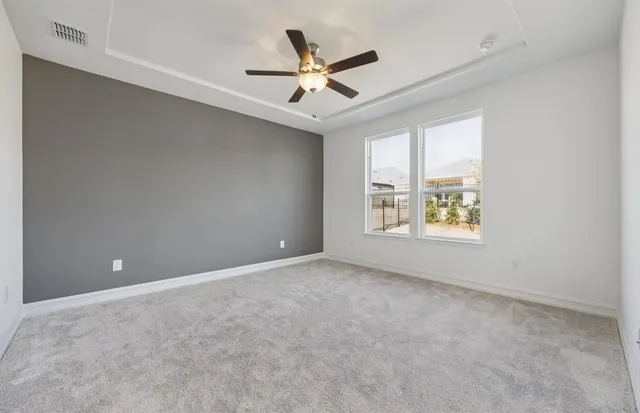 an empty room with ceiling fan and windows