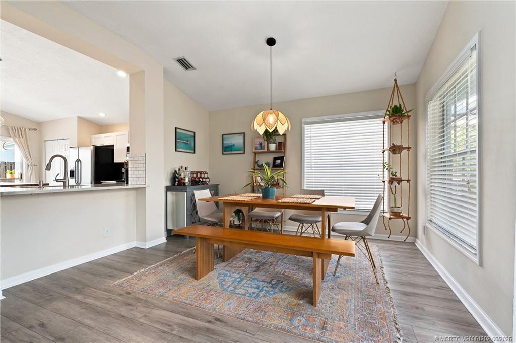 6351 Adams Street Jupiter, FL 33458 - Photo 13 of 42 a view of a dining room and a livingroom with furniture wooden floor a chandelier