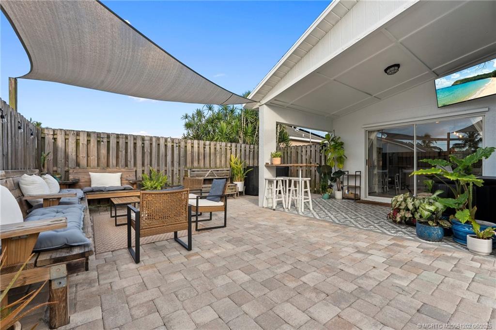 6351 Adams Street Jupiter, FL 33458 - Photo 32 of 42 a view of a patio with table and chairs potted plants and floor to ceiling window