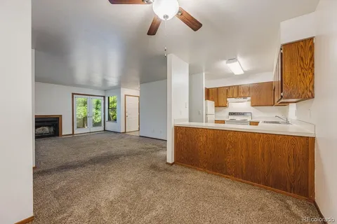 an empty room with chandelier fan and windows
