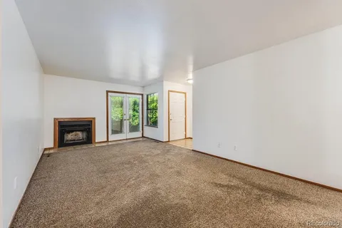 an empty room with floor to ceiling window and fireplace
