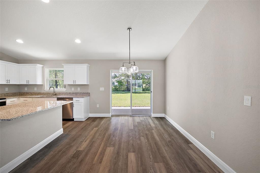 84 Pecan Run Ocala, FL 34472 - Photo 11 of 24 a kitchen with wooden floors white cabinets and stainless steel appliances