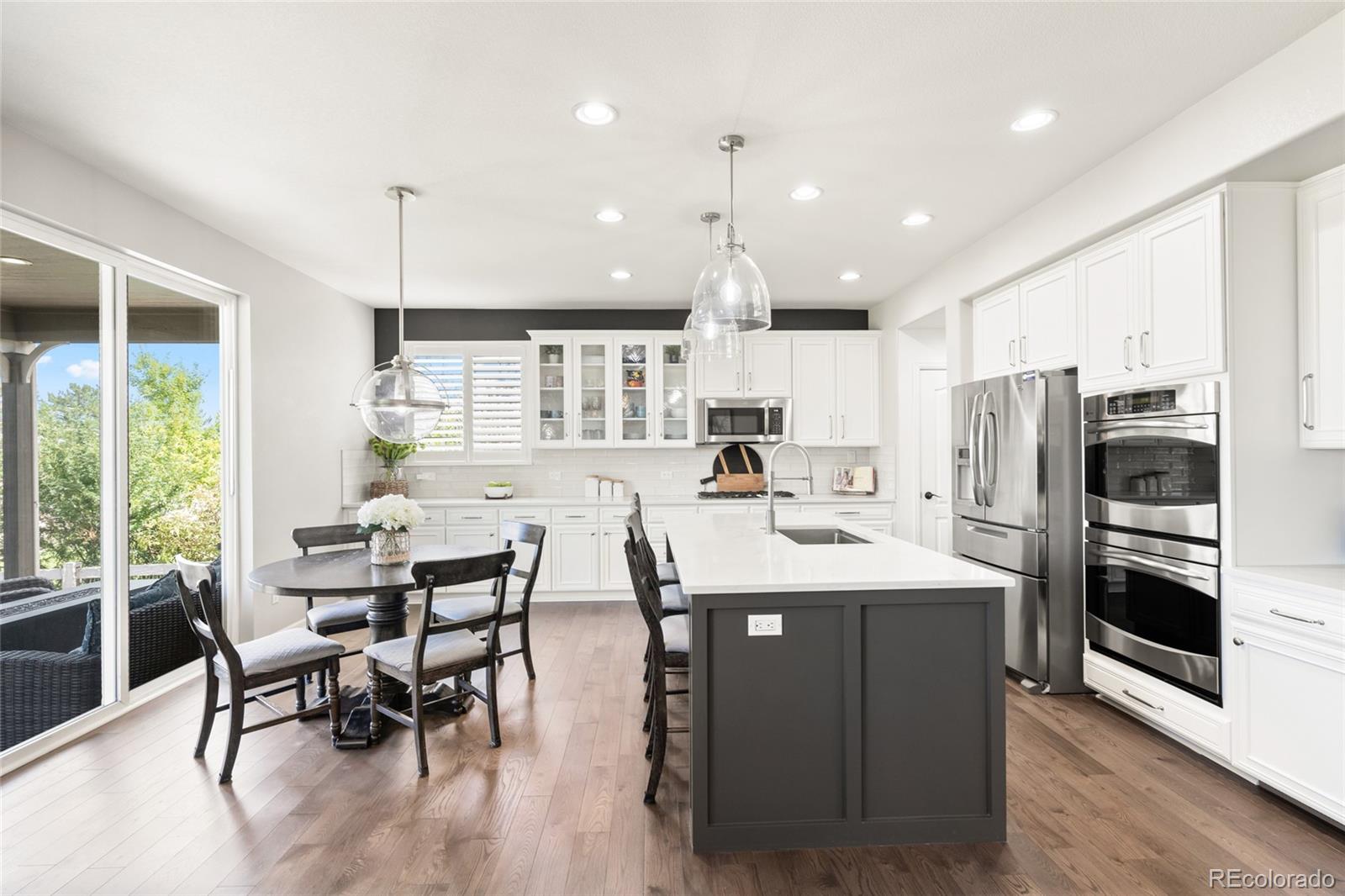 10415 Startrail Court Highlands Ranch, CO 80126 - Photo 17 of 49 a kitchen with stainless steel appliances kitchen island granite countertop a table chairs refrigerator and microwave