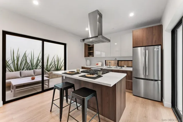 a kitchen with stainless steel appliances granite countertop a refrigerator a sink a stove a dining table and chairs