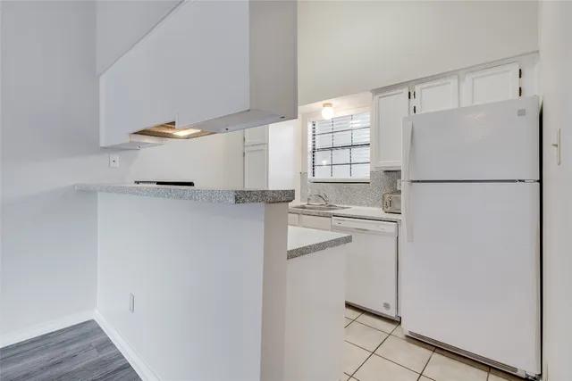 a view of a kitchen with white cabinets and wooden floor