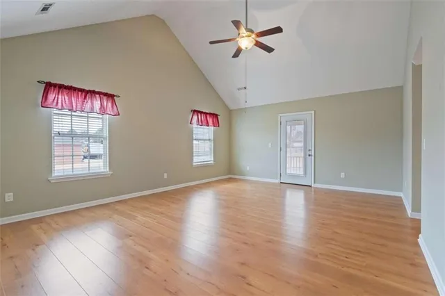 a view of an empty room with a window and wooden floor