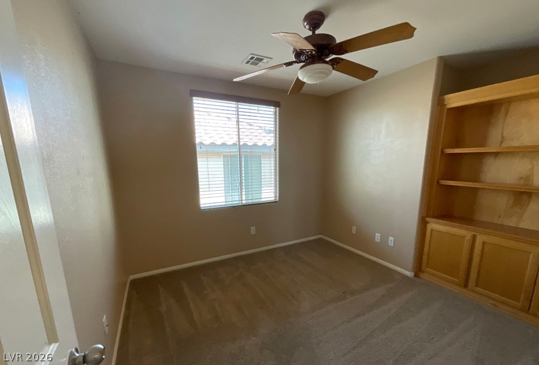 10841 Paradise Road Henderson, NV 89052 - Photo 25 of 35 A quiet bedroom offers comfort with a ceiling fan and built-in shelving for convenience.