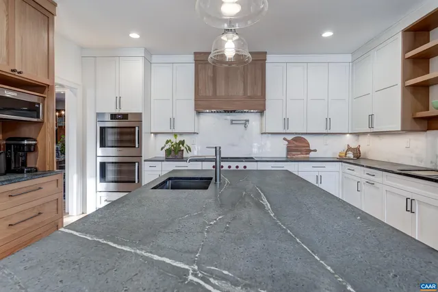 a kitchen with stainless steel appliances granite countertop a sink a stove and a wooden floors